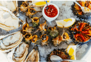 얼음 위에 올려진 신선한 생굴과 해산물, 곁들여진 레몬 조각과 소스가 함께 담긴 해산물 플래터 이미지