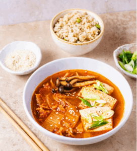 김치찌개와 현미밥, 고명으로 버섯과 두부, 파가 올려져 균형 잡힌 한 끼 식사를 보여주는 건강한 음식 이미지