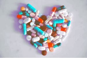 다양한 색상의 알약과 영양제가 하트 모양으로 배열된 이미지, 심혈관 건강과 영양 보충을 상징